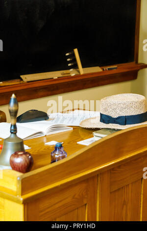 Teacher's desk at school with bell, apple, books, ink and hat on it with chalkboard  background. Stock Photo