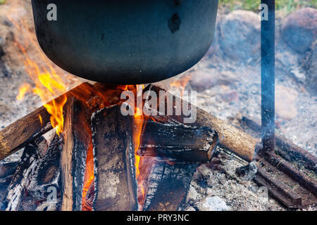 Closeup of food pot hangs over burning fire. Stock Photo