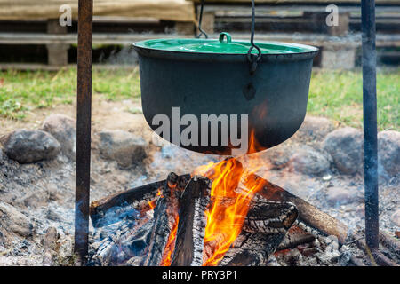 Closeup of food pot hangs over burning fire. Stock Photo