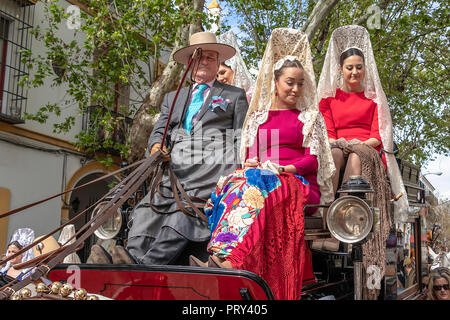 Seville, Spain - April  15, 2018: Women carries the traditional spanish head coverage called mantilla in a Horse drawn carriage in Seville April Fair  Stock Photo