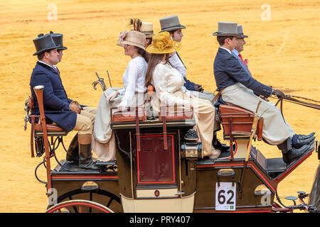 Seville, Spain - April 15, 2018: Women and men carries the traditional spanish dress up with pamela hat and top hat in a Horse drawn carriage in Sevil Stock Photo