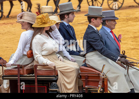 Seville, Spain - April 15, 2018: Women and men carries the traditional spanish dress up with pamela hat and top hat in a Horse drawn carriage in Sevil Stock Photo