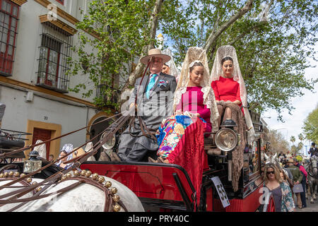 Seville, Spain - April  15, 2018: Women carries the traditional spanish head coverage called mantilla in a Horse drawn carriage in Seville April Fair  Stock Photo