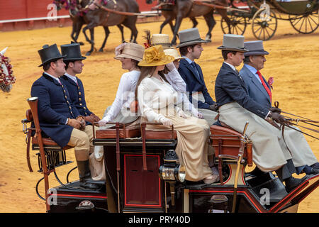 Seville, Spain - April 15, 2018: Women and men carries the traditional spanish dress up with pamela hat and top hat in a Horse drawn carriage in Sevil Stock Photo
