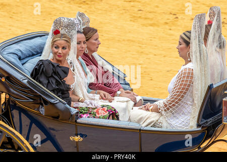 Seville, Spain - April  15, 2018: Women carries the traditional spanish head coverage called mantilla in a Horse drawn carriage in Seville April Fair  Stock Photo