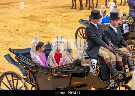 Seville, Spain - April  15, 2018: Women carries the traditional spanish head coverage called mantilla in a Horse drawn carriage in Seville April Fair  Stock Photo