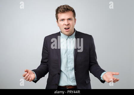 Confused angry young elegant man gestures in bewilderment, expresses negative emotions. Stock Photo