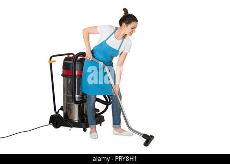 Young Female Janitor Using Vacuum Cleaner On White Background Stock Photo