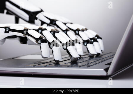Close-up Of Robotic Hand Typing On Laptop Keypad Stock Photo