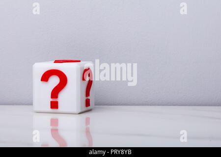 White Cubic Block With Question Mark Sign In Front Of Wall Stock Photo