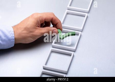Man's Hand Placing Green Check Mark In Box On Grey Background Stock Photo