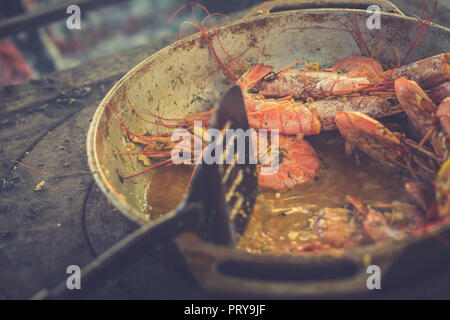 Several appetizing large shrimps in sauce with lemon lie in a frying pan. Toned image Stock Photo