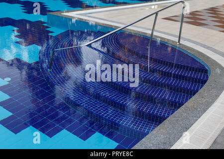 Semicircular steps of blue colour in the large pool with clear water Stock Photo
