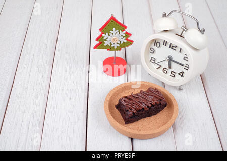 Alarm clock, note clipper and  chocolate brownie with melted chocolate on a wooden plate Stock Photo