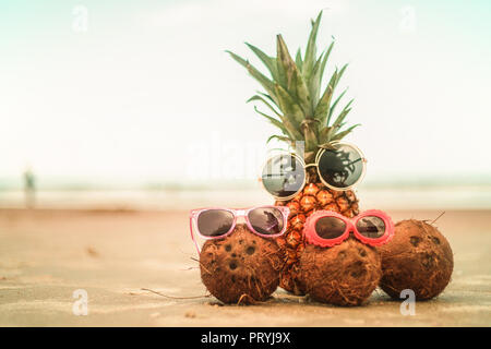Pineapple and Coconuts Wearing Sunglasses On Sandy Beautiful Beach Stock Photo