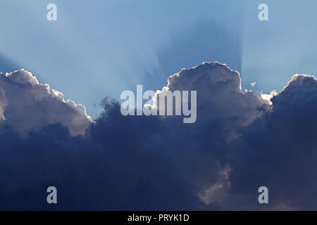 angry storm clouds gathering in late August in Italy with the sun's rays shining behind Stock Photo