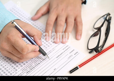 Top view of filling OMR sheet heading with pen. Picture of glasses and pencil on the table. Stock Photo