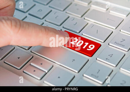 finger pressing keyboard key written 2019 newyear. finger presses a button on the gray keyboard. Beginning of new year Stock Photo