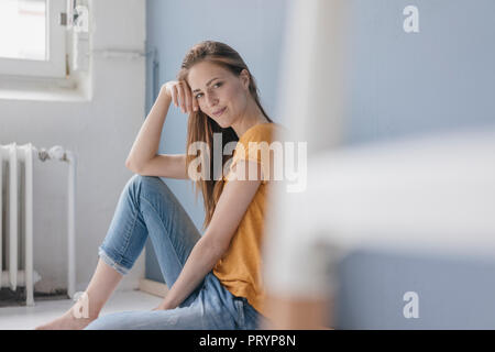 Smiling woman sitting on floor of her new home Stock Photo