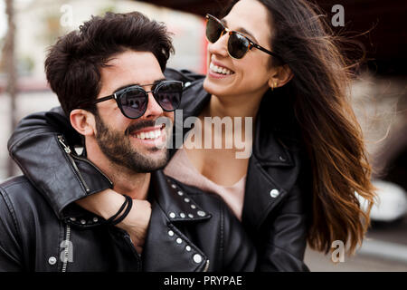 Portrait of happy young couple wearing sunglasses and leather jackets Stock Photo