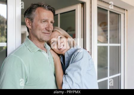 Portrait of smiling mature couple at French window Stock Photo