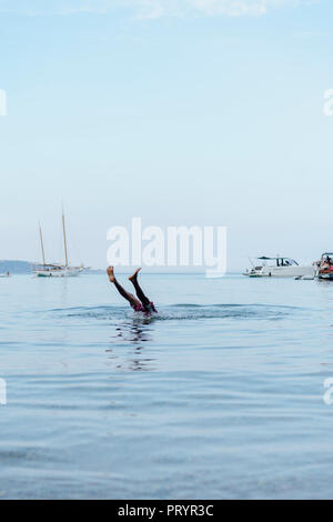 Man doing handstand in water, falling down Stock Photo