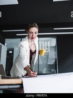 Businesswoman in office working on plan at desk Stock Photo