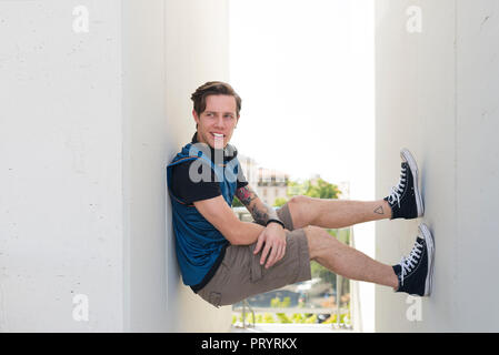 Portrait of tattooed young man in a gap between two facades Stock Photo