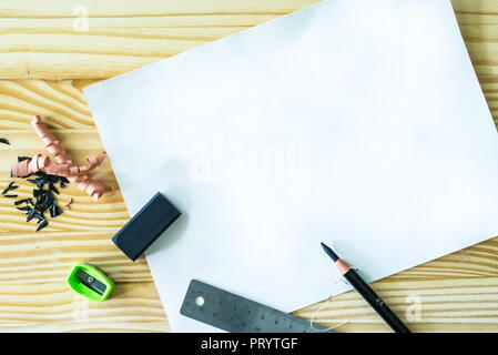 Blank white drawing paper on the wooden desk with pencil, eraser, sharpener and steel ruler Stock Photo