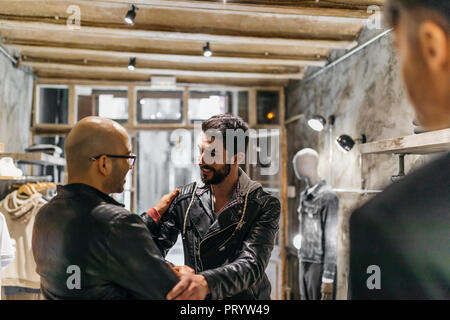 Two smiling men meeting in modern menswear shop Stock Photo