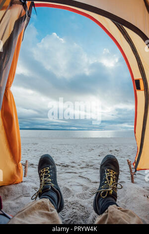 Feet of man, lying in tent on beach Stock Photo