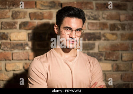 Portrait of serious young man at brick wall Stock Photo