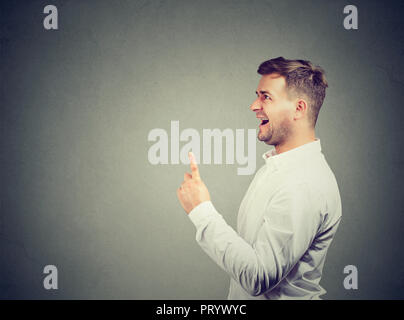 Eureka! Young business man with one finger up has an idea isolated on gray background Stock Photo