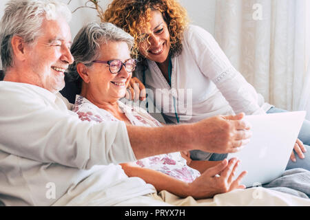 family team at work at home sit down on the sofa. smile and have fun working on a laptop together. mother father and daughter aged senior use technolo Stock Photo