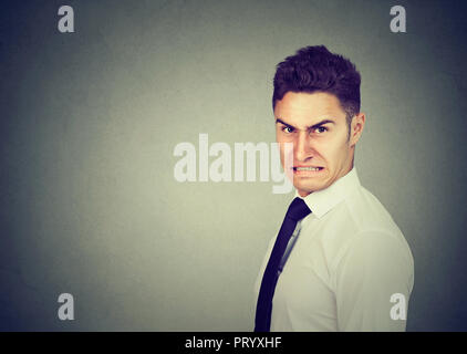Formal man in shirt with displeased grimace looking grumpy at camera on gray background Stock Photo