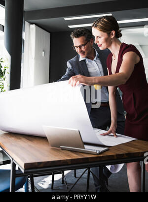 Businesswoman and businessman in office discussing plan on desk Stock Photo
