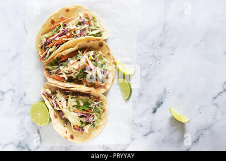 Tacos with guacamole and coleslaw served with lime slices on a light background. Stock Photo