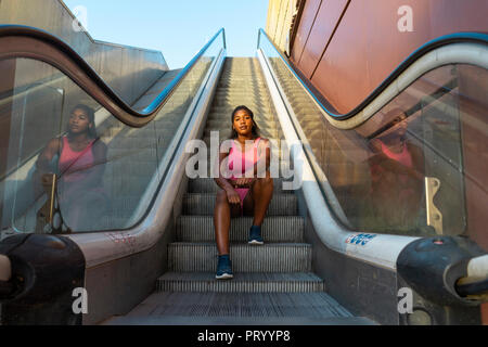 Young sportive woman sitting on escalator Stock Photo