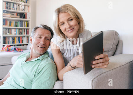 Smiling mature couple at home using tablet Stock Photo