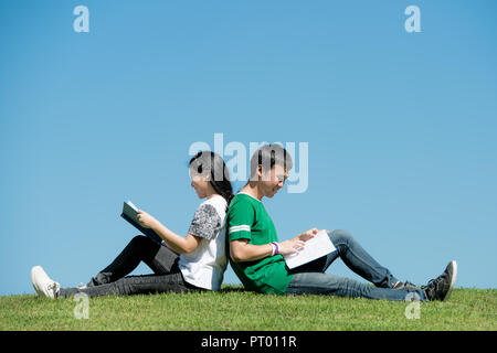 Asian couple student reading book together at outdoors park in university Stock Photo