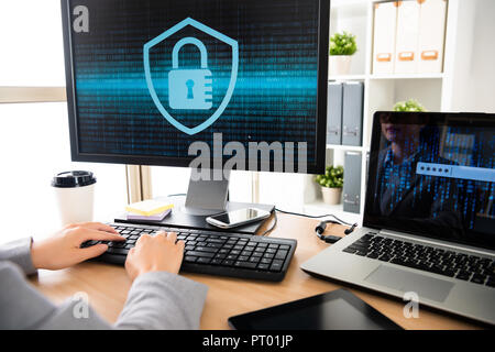 female employee who works in personal information safety company is sitting in front of her office desk and trying to unlock her computer Stock Photo