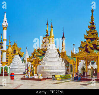 YANGON, MYANMAR - FEBRUARY 27, 2018: The picturesque white stupa with carved stucco patterns is the replica of hti umbrella (upper part of pagoda) in  Stock Photo