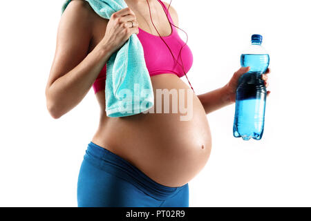 Resting time. Close up of pregnant woman in sportswear holding towel and bottle of water isolated on white background. Concept of healthy life Stock Photo