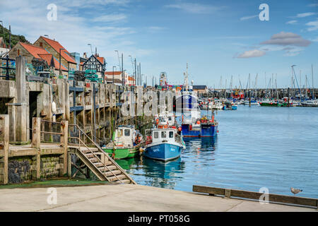 Four pretty coloured fishing boats moored up in the famous harbour of the Yorkshire seaside town of Scarborough on the North East coast of England. Stock Photo