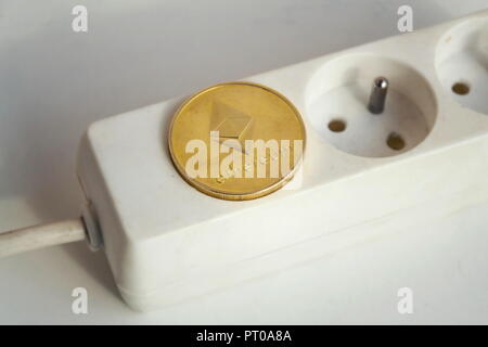 Ethereum coin lying on power strip extension cord with empty socket, cryptocurrency energy consumption and footprint concept, isolated on white backgr Stock Photo