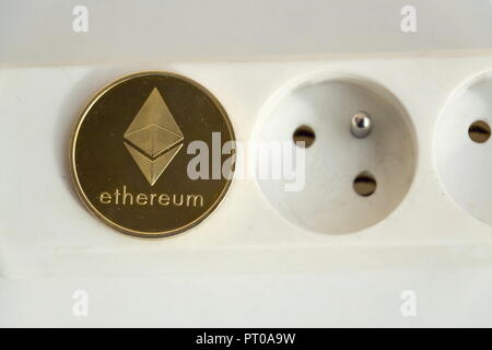 Ethereum coin lying on power strip extension cord with empty socket, cryptocurrency energy consumption and footprint concept, isolated on white backgr Stock Photo