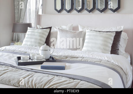 Decorative tray with book and tea set on the bed in modern bedroom Stock Photo