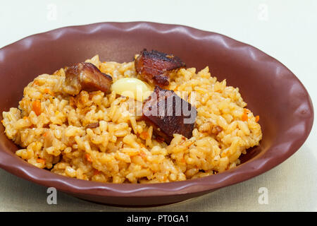 Rice pilaf with meat and vegetables on clay plate on white napkin Stock Photo