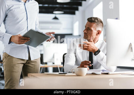 Cropped image of Two colleagues working together with documents while being in office Stock Photo