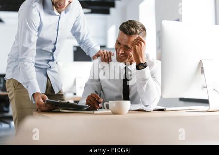 Cropped image of two happy colleagues working together with documents while being in office Stock Photo